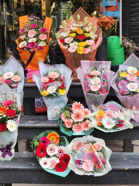 A display of various floral bouquets arranged on outdoor wooden steps, featuring an assortment of fresh flowers including pink, white, yellow, and red daisies, carnations, and chrysanthemums. The bouq