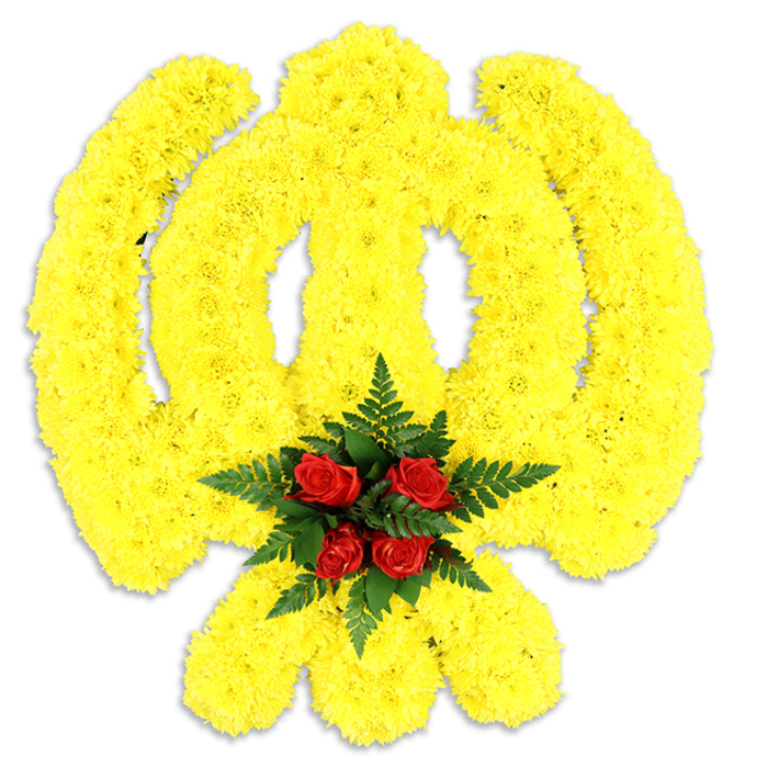 A large, ceremonial Khanda constructed from innumerable small, bright yellow chrysanthemum blooms dominates a white photographic field, the kind of floral workmanship that reads as both devotional symbol and sculpted object. The yellow flowers are packed densely to form clean, continuous lines - the rounded chakkar, the upright double-edged sword and the pair of crossed kirpans at the base - all rendered with a rhythm of petals that creates depth and a slightly raised, tactile effect. The hue is a warm, sunny yellow, vivid against the white ground, and the petal edges catch light so that the emblem seems to glow faintly from within. At the very centre, where the emblem's geometry meets, a compact cluster of five to six rich red roses is arranged with intentional restraint; their dark, velveteen petals read as a quiet, solemn heart to the composition. Lush, deep green fern fronds cradle the roses, introducing a cool, textured border that heightens the red-yellow contrast and lends a natural frame to the focal point. A soft grey shadow beneath implies solidity and shows that this is a freestanding tribute - appropriate as a funeral wreath, memorial centerpiece, or ceremonial offering during an event honouring Sikh faith and remembrance. The overall scent is gentle - green and floral with a transient rose note - and the craftsmanship reflects local florist practice in Lea Bridge and surrounding Leyton and Walthamstow communities, where such respectful, symbolically accurate tributes are often requested for cultural services.