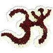 A reverent floral depiction of the sacred Om (Aum) symbol rests against a pure white backdrop, every curve hand-modeled from tightly clustered blooms so the emblem reads like a carved relief. The central mass is built from small, deep maroon to burgundy chrysanthemum-like flowers whose velvety petals collect light and shadow; many of these tiny heads reveal a surprising lime-green eye at their centers, a quiet, botanical punctuation that adds texture and life to the dark field. Around this rich interior runs a generous, undulating frame of pristine white spray chrysanthemums, their fine petals forming a luminous outline that sharpens the symbol's distinctive '3' curve, the flowing lower stroke and the crescent-and-dot above. The arrangement's surface is soft yet sculptural, suggesting the cool, satiny touch of petal layers pressed close together; a subtle drop shadow on the white background gives the work presence and a respectful gravity, as if it were elevated on a shrine. There is a faint, comforting scent-an earthy, late-summer hint of chrysanthemum and damp foliage-that grounds the piece in the senses and suits quiet observance. Made with the attention of a seasoned florist, the composition feels suited to moments of meditation, memorial remembrances, or cultural celebration, and would sit naturally in a small chapel, a community shrine or the centre of a spiritual gathering. For locals, this floral Om resonates with the calm corners of Lea Bridge Park and the gentle flow of the River Lea, offering a visual pause and an atmosphere of calm and dignity.